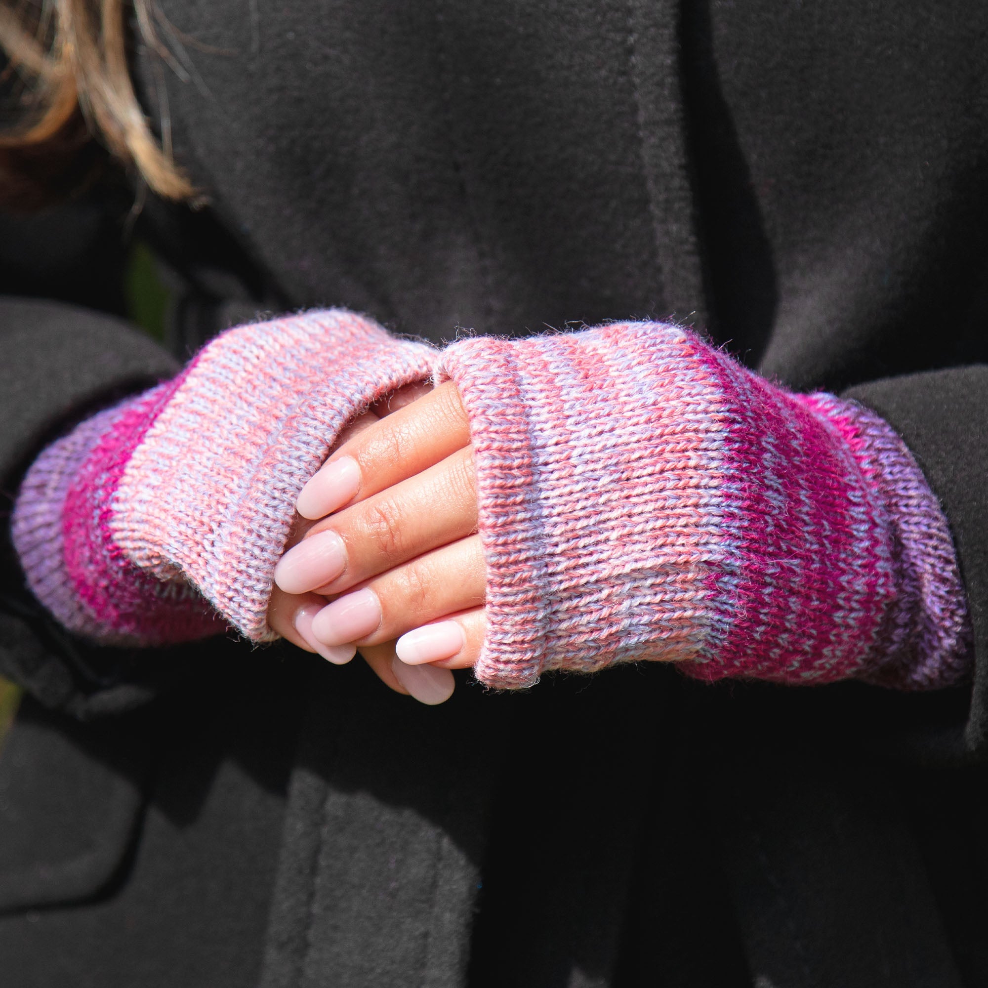 Close-up of hands wearing handmade alpaca fingerless mittens, highlighting the colorful knit pattern and soft, textured fibers.