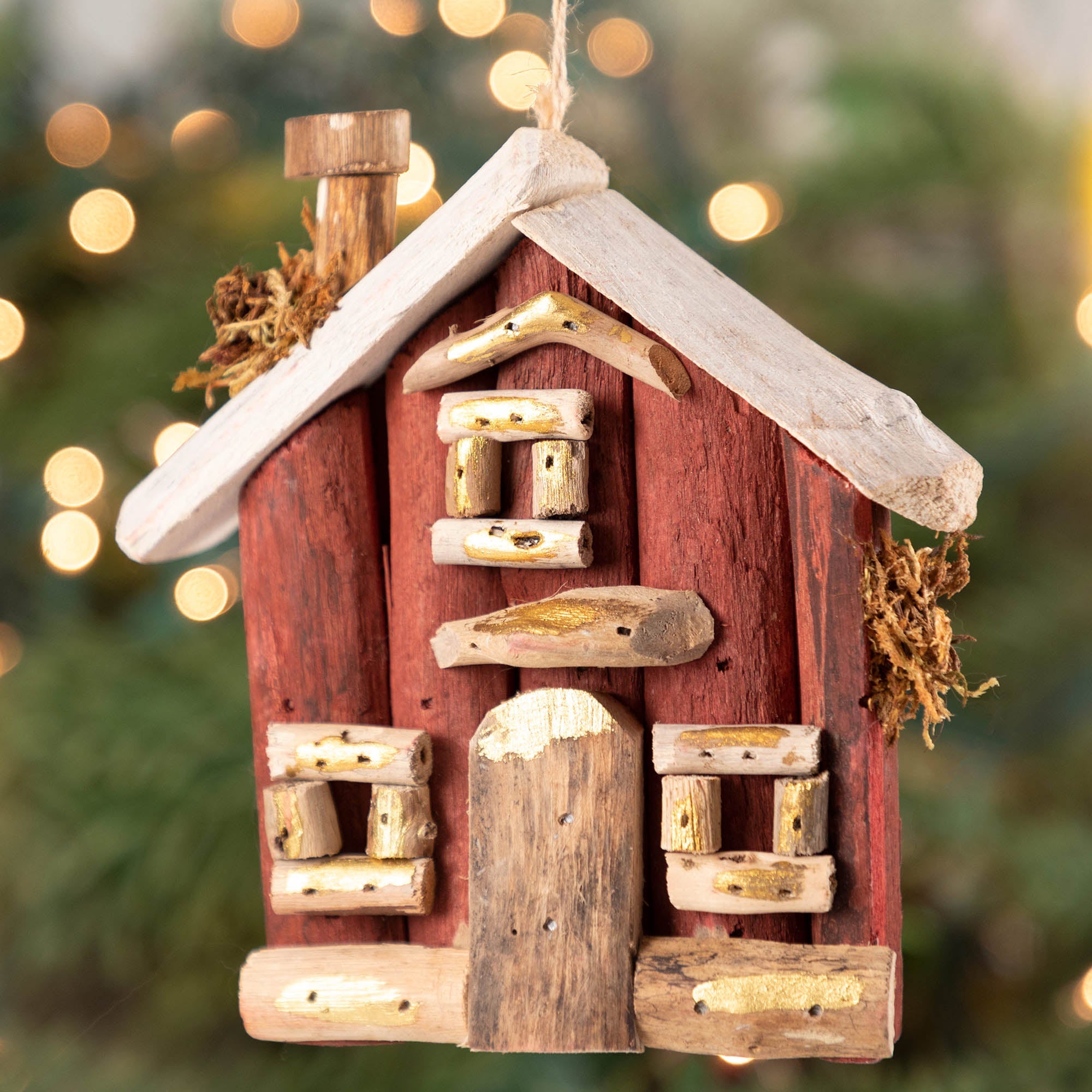 Driftwood burgundy Christmas house ornament hanging by natural twine against a festive backdrop. Features hand-carved details and sustainable materials from the Philippines.