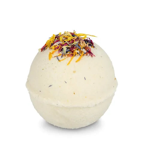 A single light-colored bath bomb is shown against a white background. The top of the bath bomb is decorated with a colorful mix of dried petals and herbs that look like confetti.
