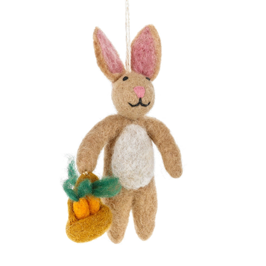 A handmade felt brown rabbit is shown holding a small felt basket with three orange carrots.