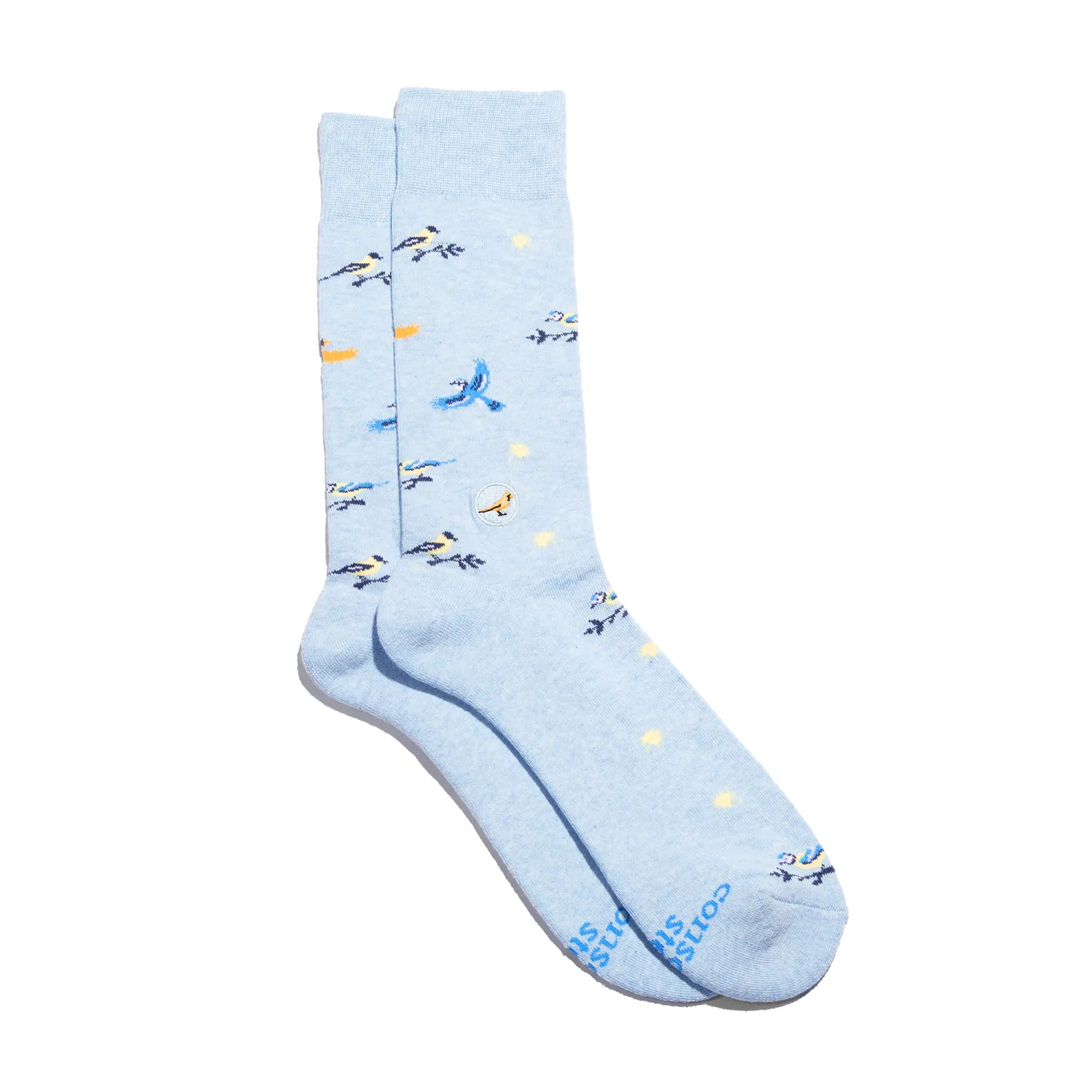 A pair of light blue Conscious Step socks with a pattern of blue and yellow birds is shown against a white background. The socks also have small yellow flower shapes and the brand name is visible on the bottom.