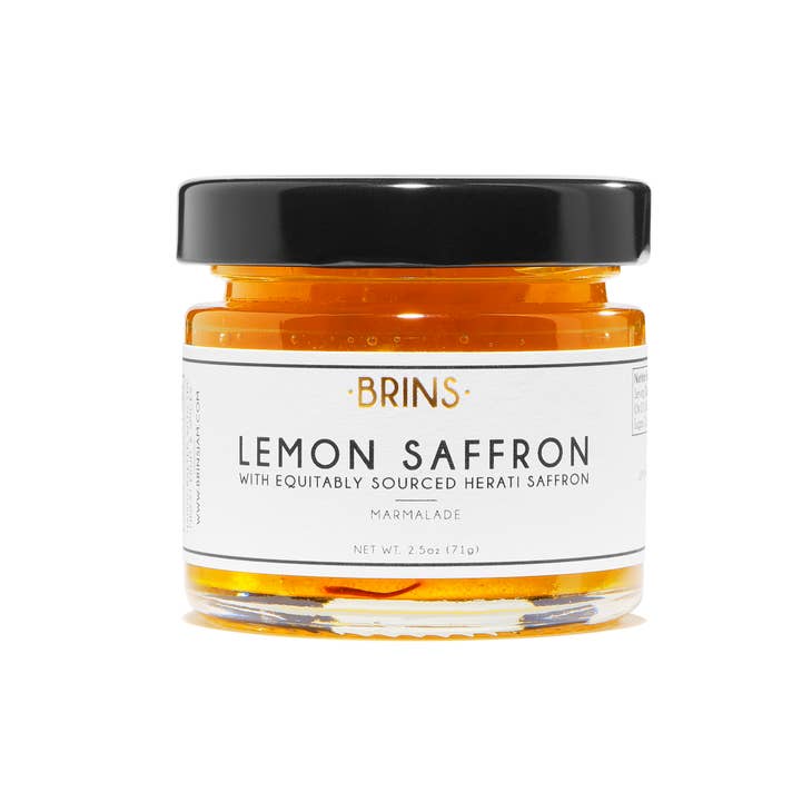 A small glass jar of "BRINS" Lemon Saffron marmalade with a black lid. The white label features the flavor and a description, "WITH EQUITABLY SOURCED HERATI SAFFRON" in black text. The bright yellow marmalade is visible inside the jar.