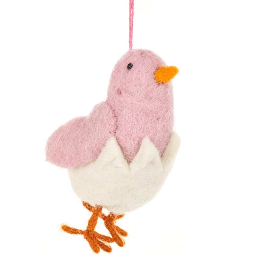 A handmade felt hanging decoration features a light pink chick with an orange beak and feet emerging from a white cracked eggshell.