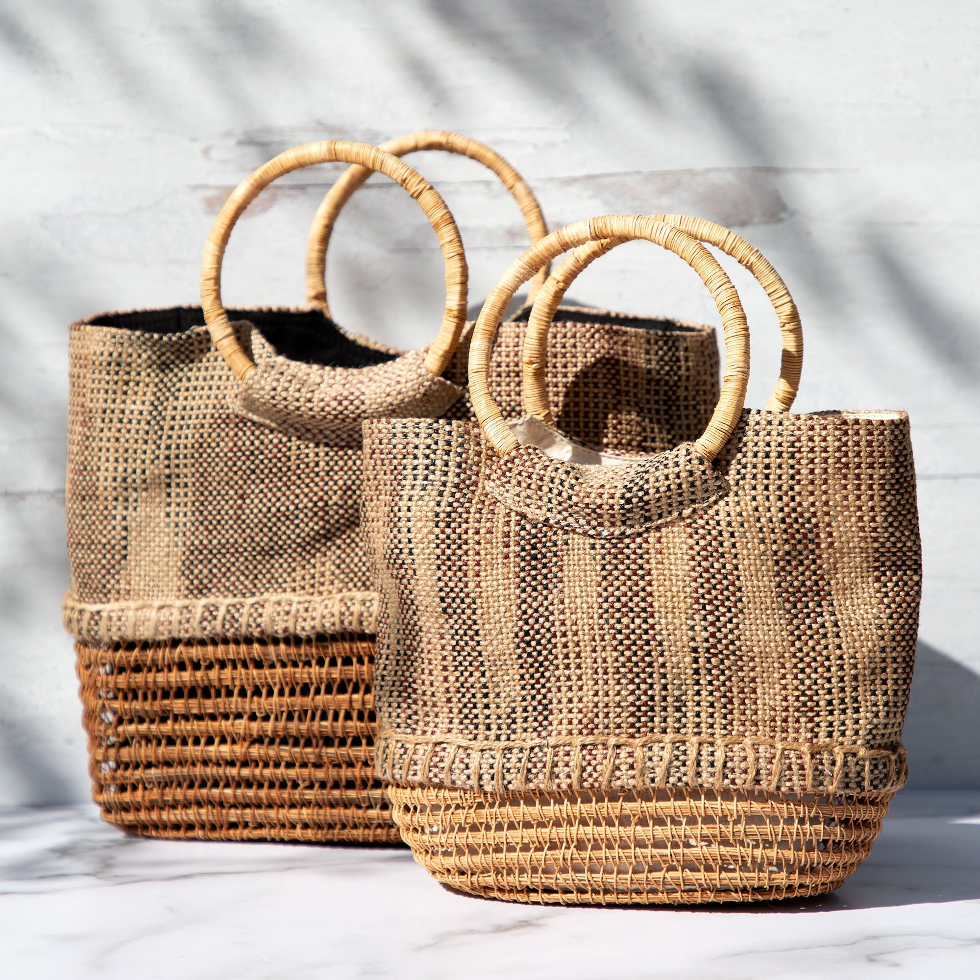 Palm fiber totes in large and small sizes placed together, showing off their handmade texture, sturdy construction, and versatile shape.