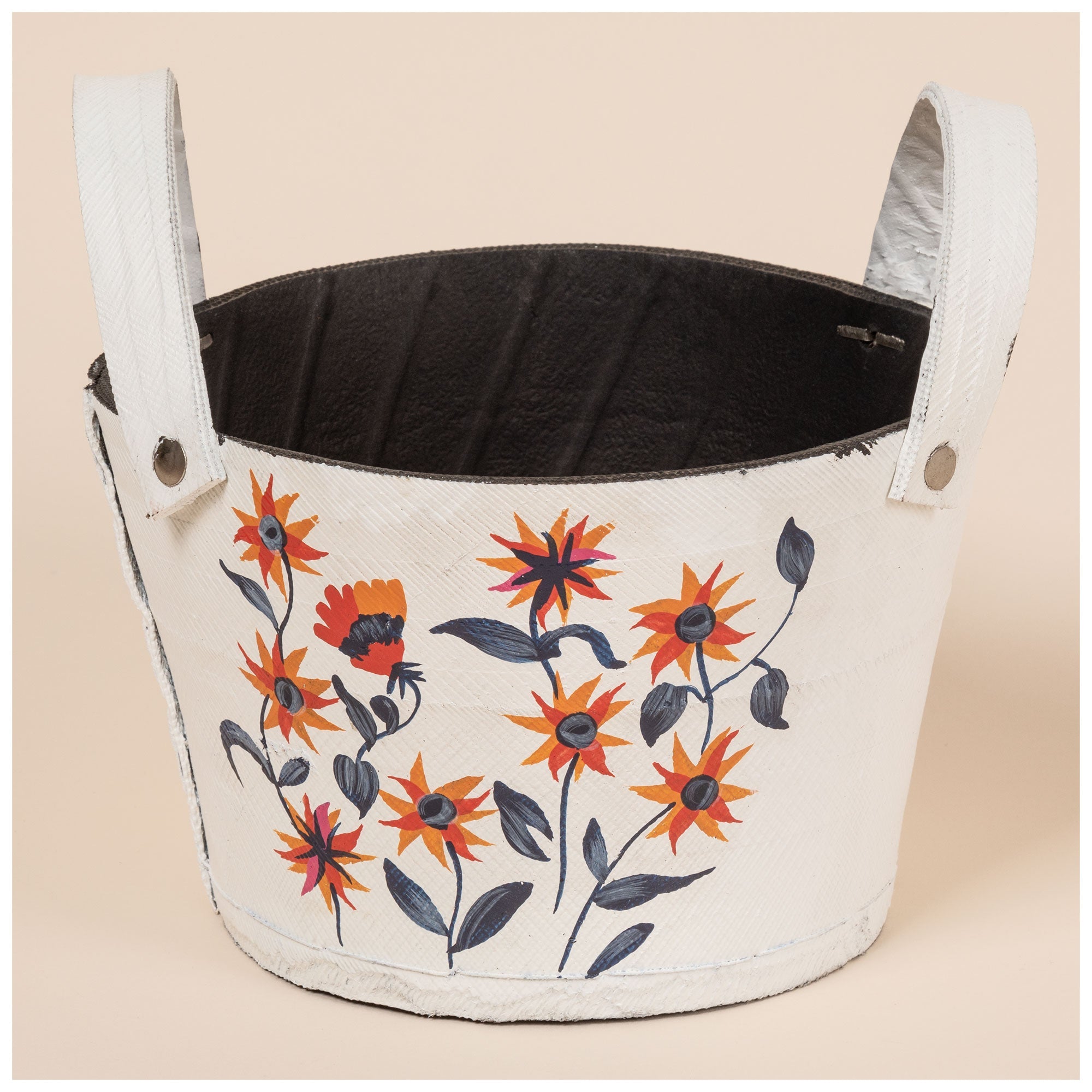 Small white planter made from recycled rubber, hand-painted with orange flowers and green leaves. Black interior visible with curved handles on both sides.