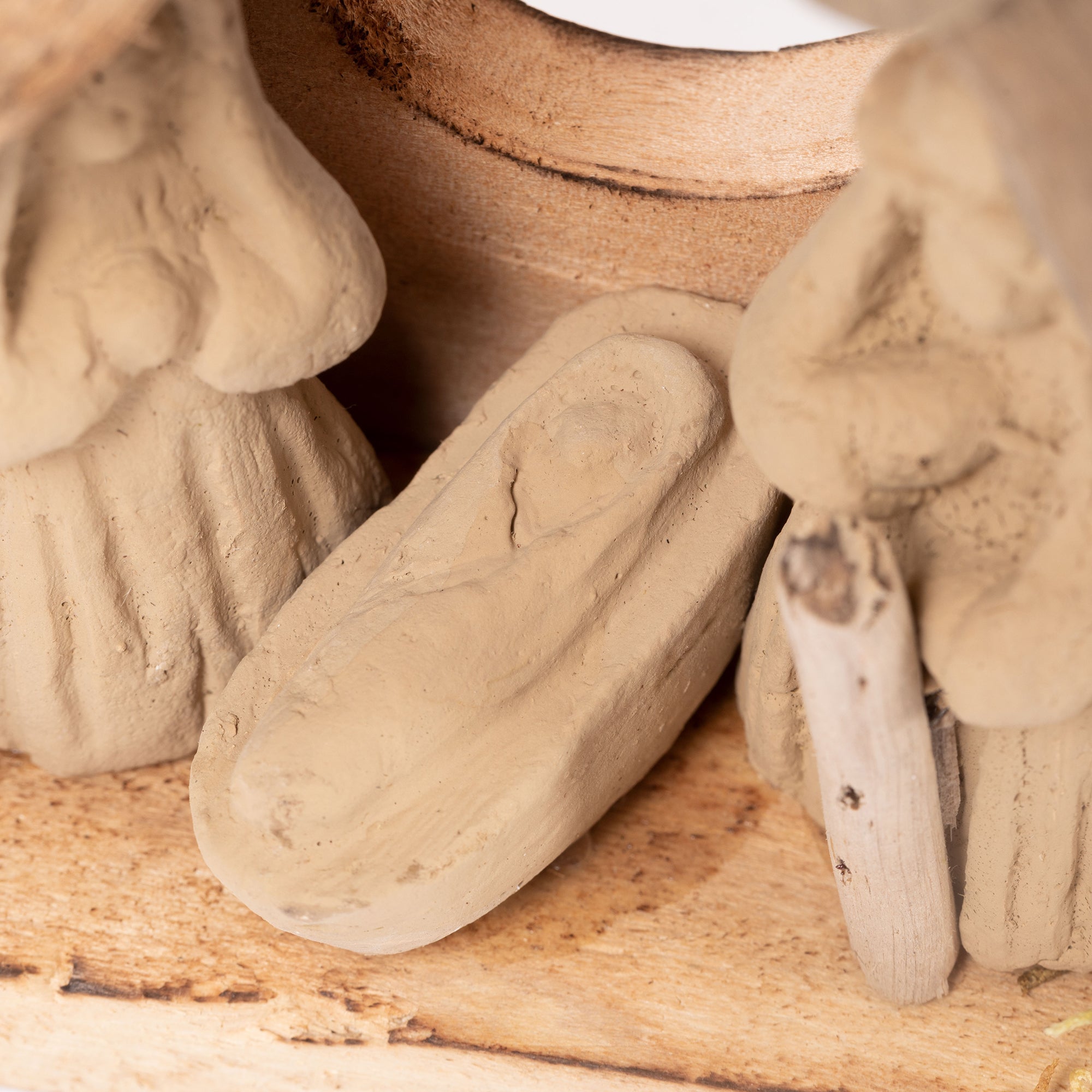 Closeup of handmade recycled clay baby Jesus figure in driftwood nativity ornament with detailed natural texture.