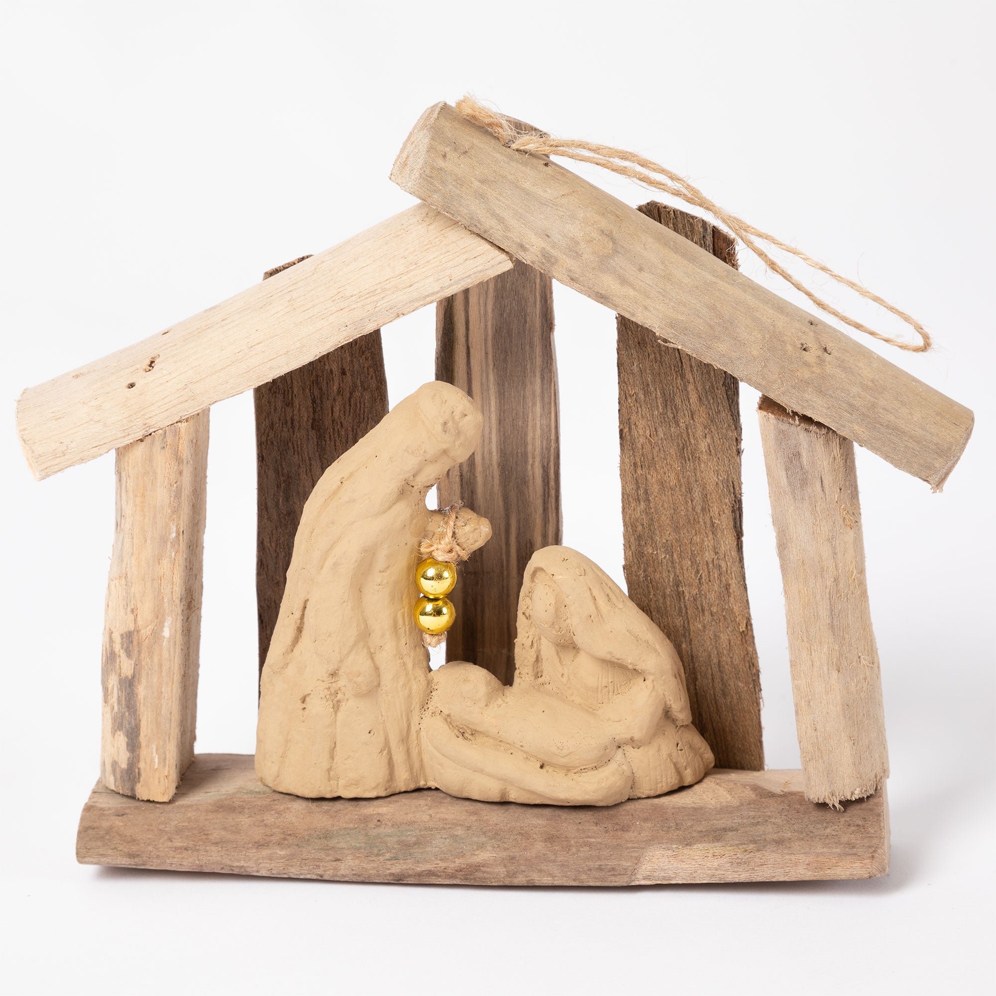 Recycled, handmade driftwood nativity ornament with clay figures of Mary, Joseph, and baby Jesus under a rustic driftwood roof with hanging rope.