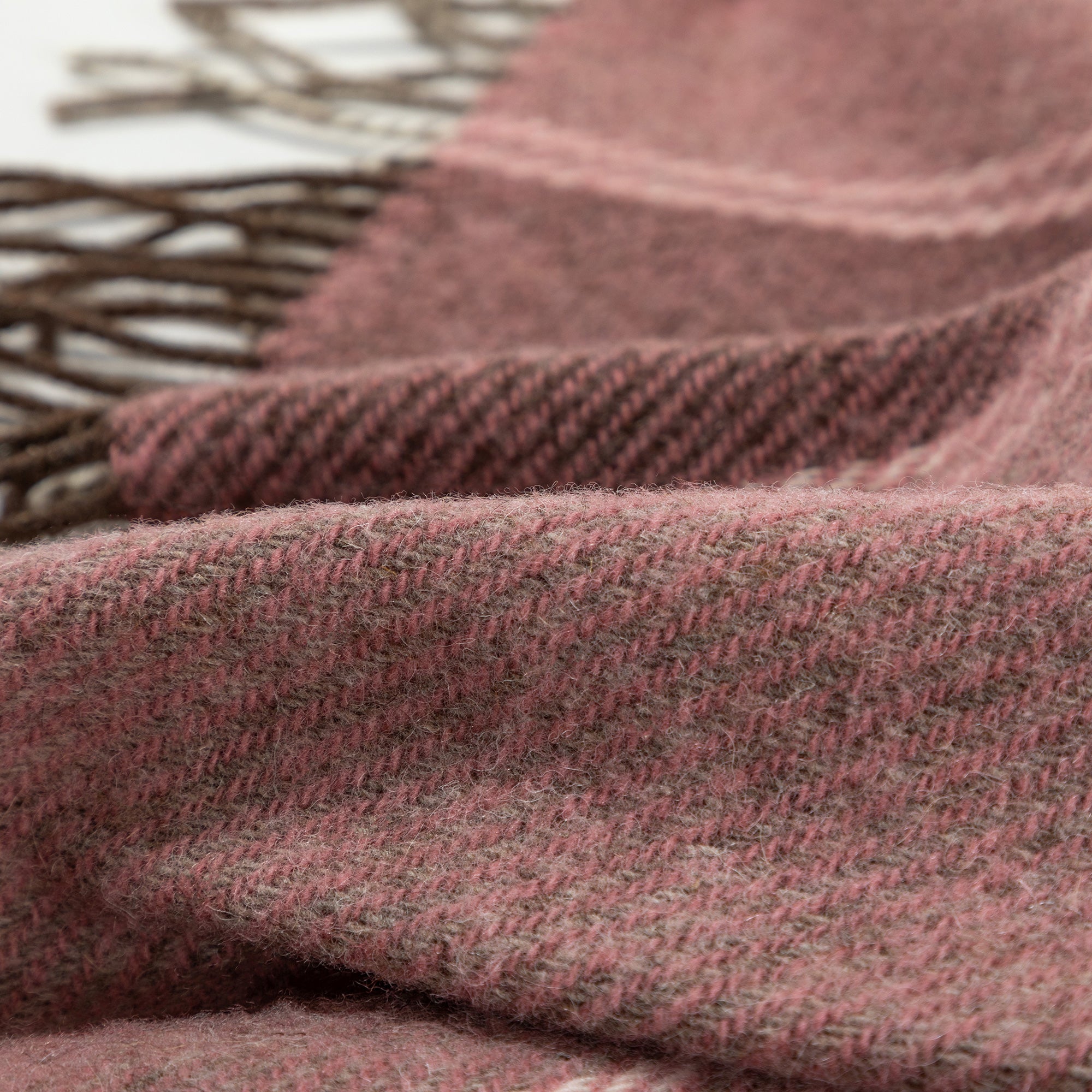 Close-up of a Ukrainian wool throw blanket in burgundy, draped over a soft surface to show texture and fringe.