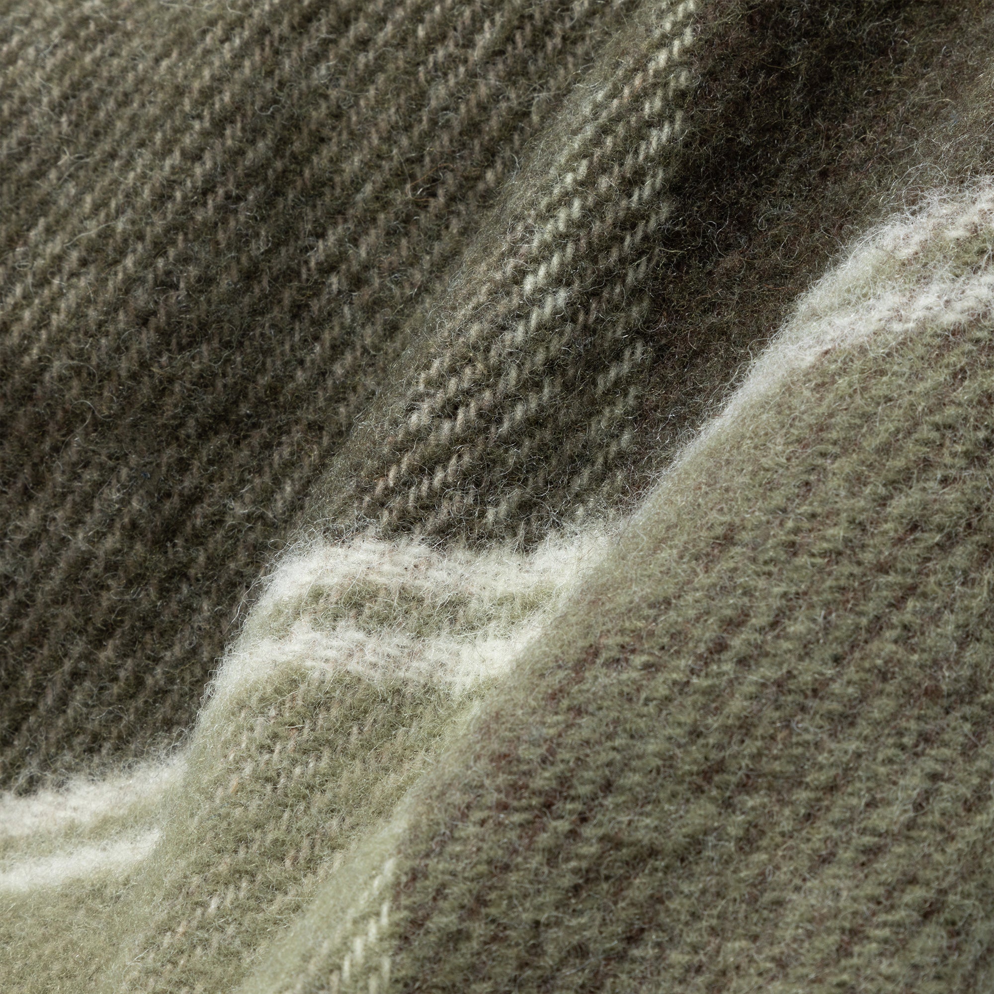Close-up of the green and brown plaid wool throw blanket showing its soft, textured weave and natural wool fibers. Made in Ukraine.
