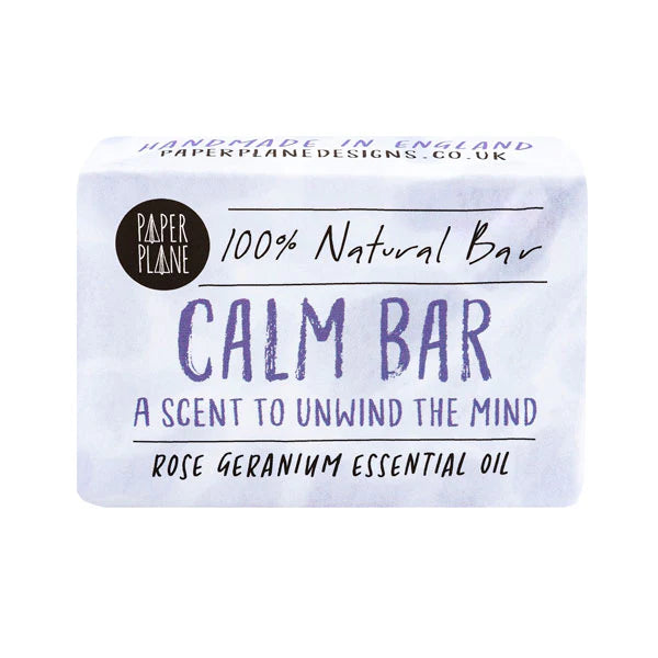 A recycled paper wrapper for a "Paper Plane" "Calm Bar" is shown. The wrapper notes that it is a "100% Natural Bar" with "Rose Geranium Essential Oil" and is handmade in England.