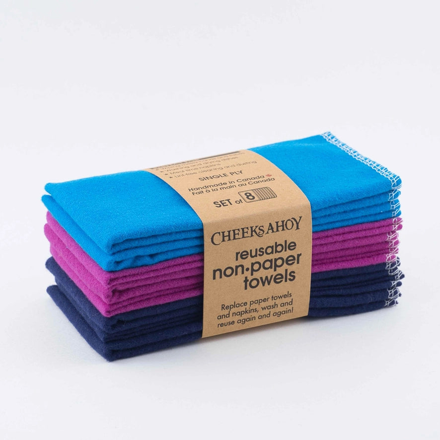 A stack of eight Cheeks Ahoy reusable non-paper towels is shown in shades of blue and magenta. The cloths are held together by a paper band that identifies them as a set of eight single-ply towels.