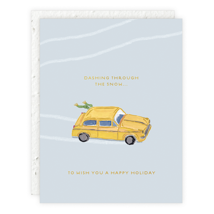 A light blue holiday card with white snow tracks and a yellow car carrying a Christmas tree tied to its roof. Text reads: "Dashing through the snow... To wish you a happy holiday."