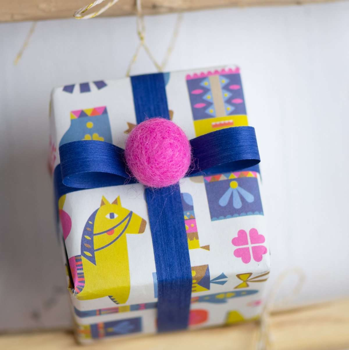 Soft blue natural cotton curling ribbon tied around a wrapped gift, made from 100% cotton yarn dyed with eco-friendly water-based dyes. Compostable and sustainably produced in the USA.
