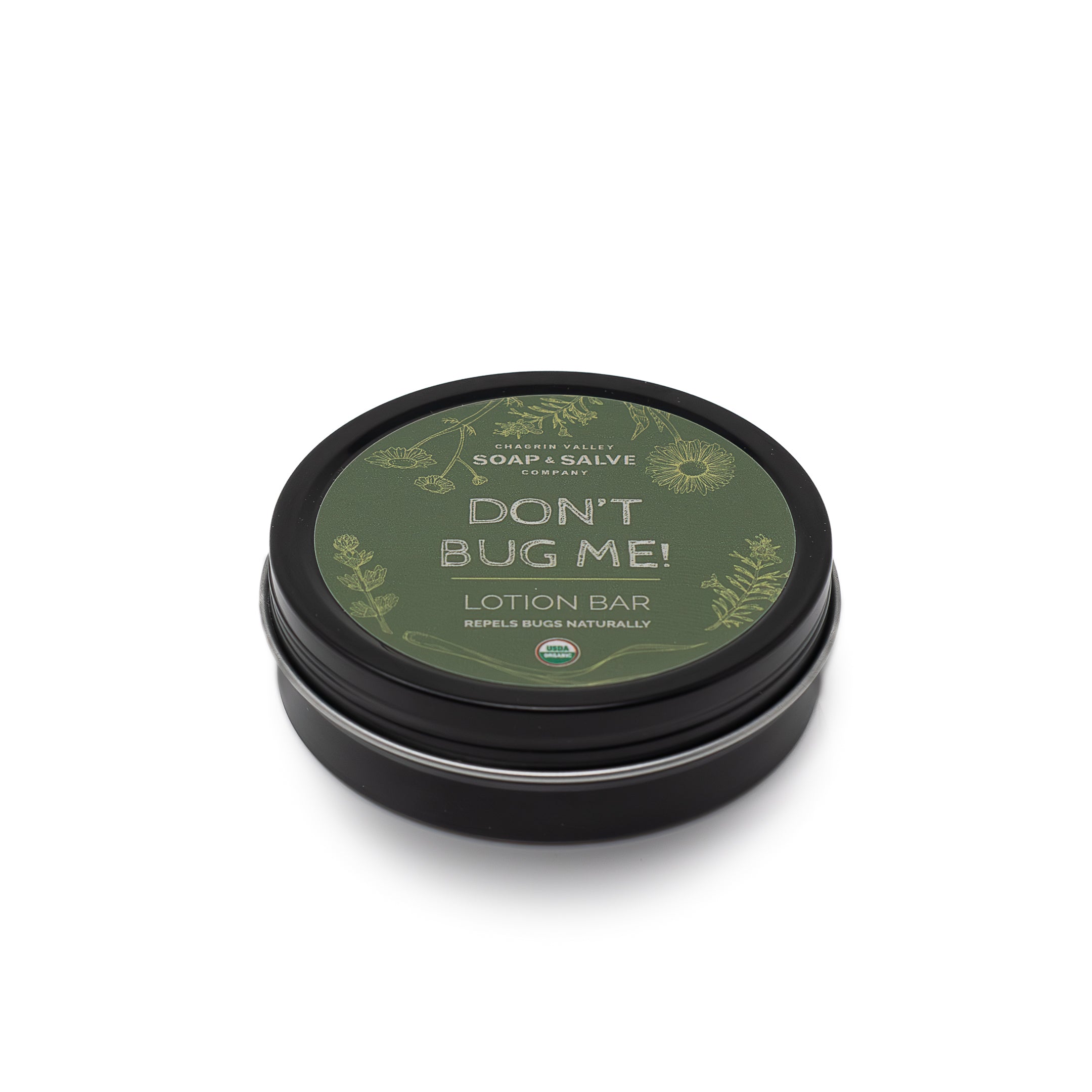 A black tin with the lid closed. The lid has a green label for 'Chagrin Valley Soap & Salve Company's' 'Don't Bug Me!' lotion bar. The label also states that it "repels bugs naturally" and includes a small "USDA Organic" logo.