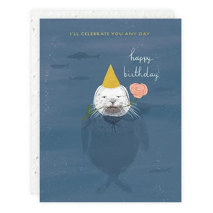 Seal wearing a party hat with a pink flower in its mouth, set against a blue background with gold foil birthday text.