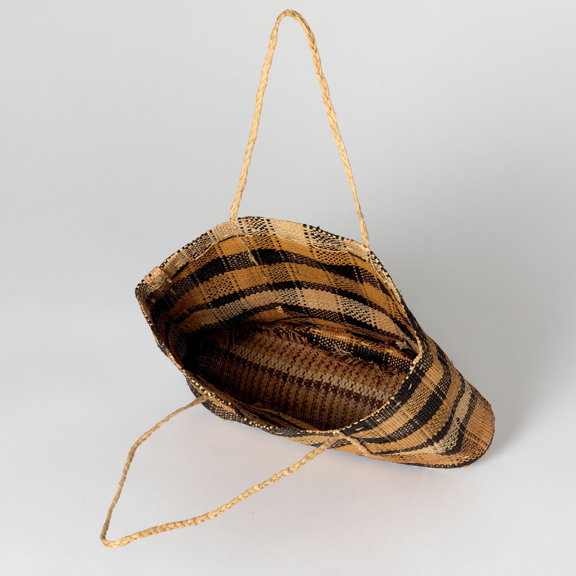 Handwoven tote bag in varying brown tones, highlighting the unique texture and open weave. Created by Congolese artisans promoting fair-trade and community support.