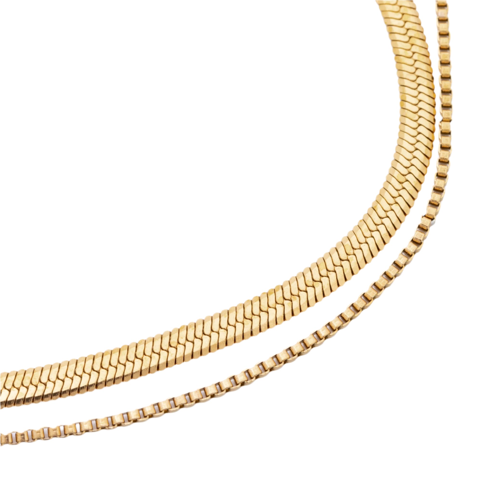 A close-up view of a gold necklace displayed against a neutral background, showcasing its intricate design and shiny finish.