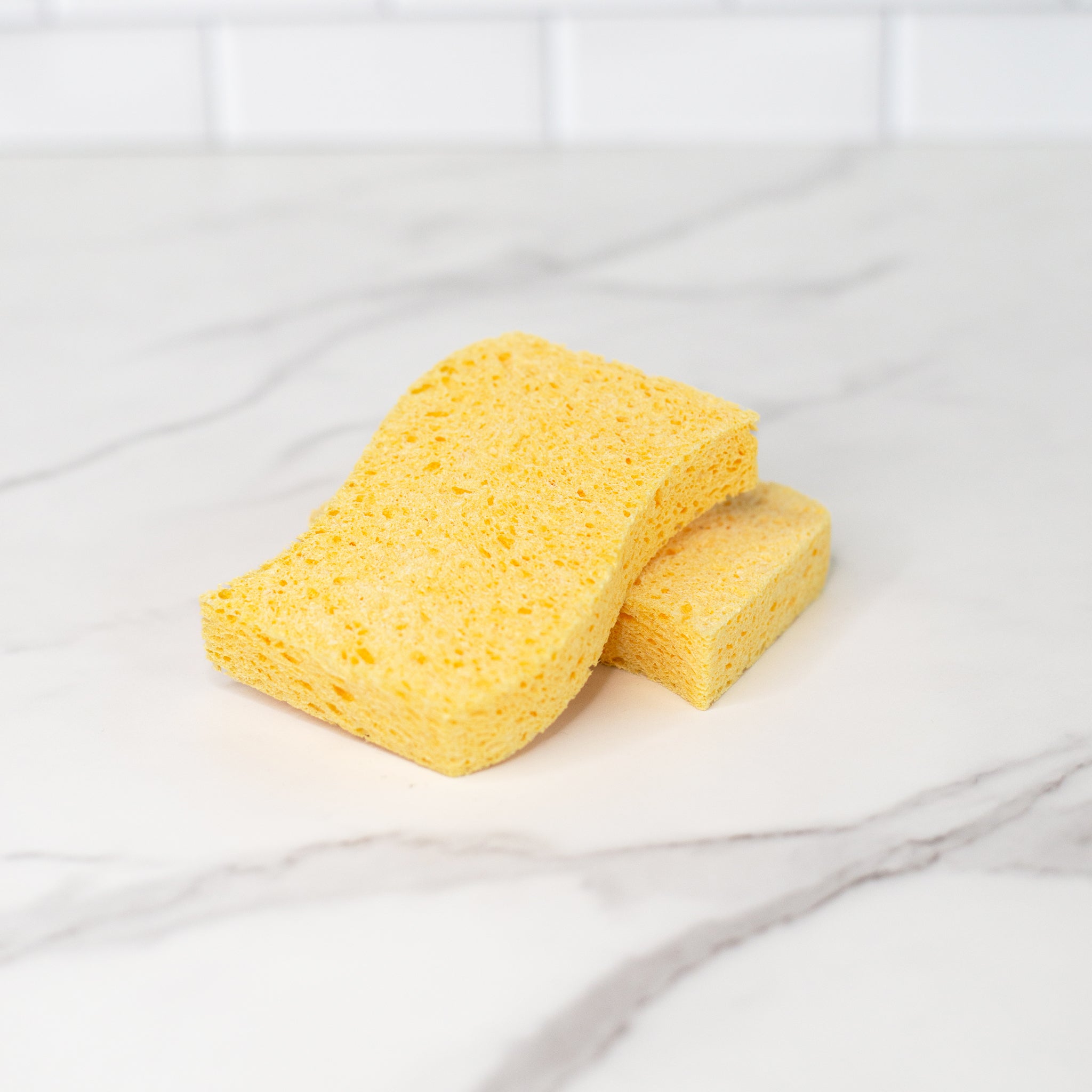 Two natural plant cellulose biodegradable kitchen sponges in a marble surface.