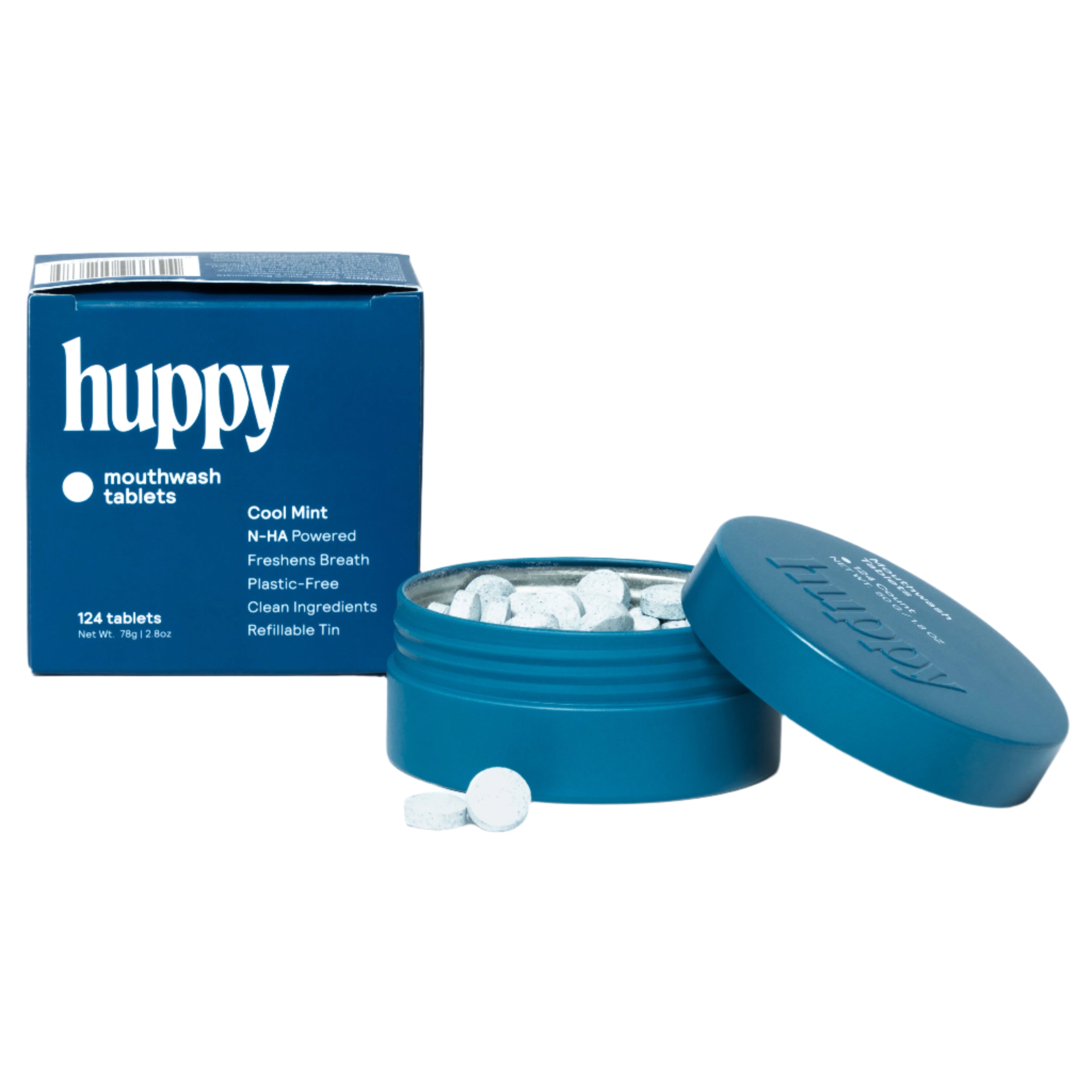 A cute blue tin of Huppy mouthwash tablets is open next to its refill box. The box says "Cool Mint" and highlights the plastic-free, refillable nature of the product, with a few tablets visible outside the tin.