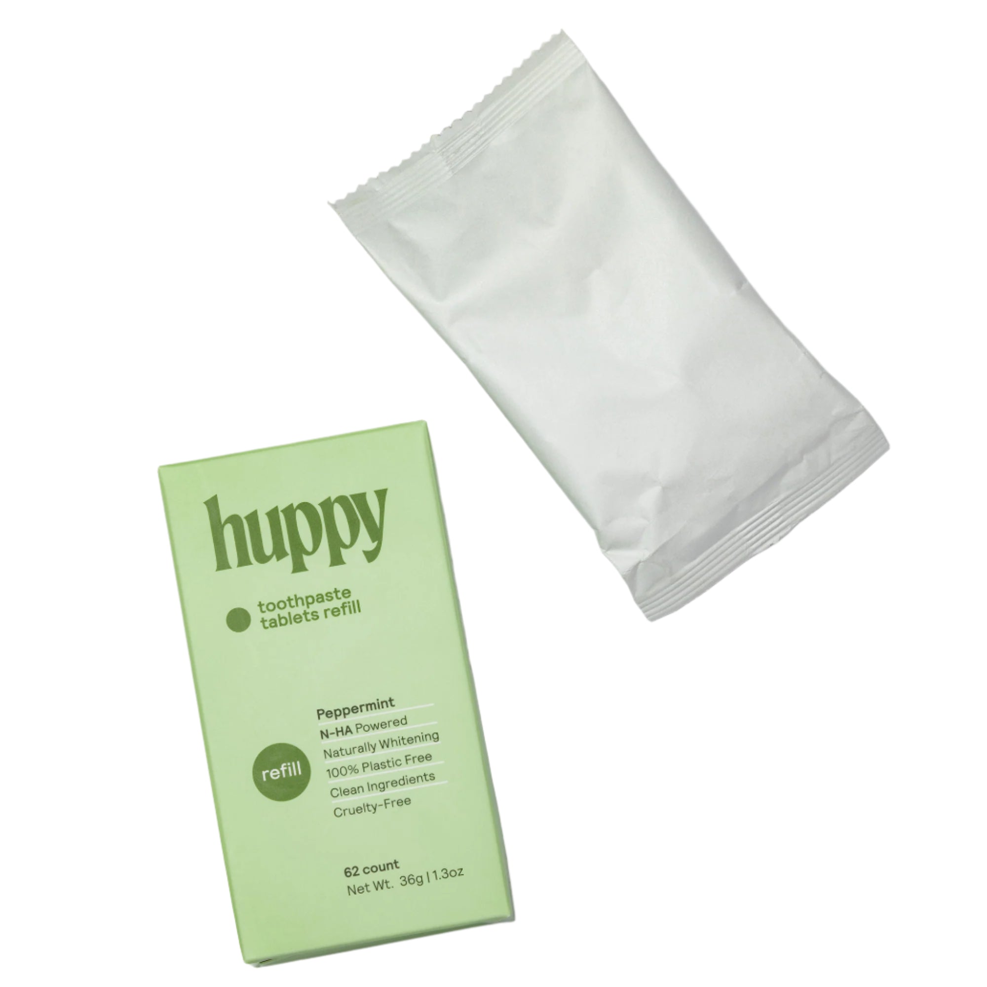 A green cardboard refill box for 'huppy' toothpaste tablets is shown next to its compostable white pouch. " This little pouch is the perfect eco-friendly way to refill your tin.