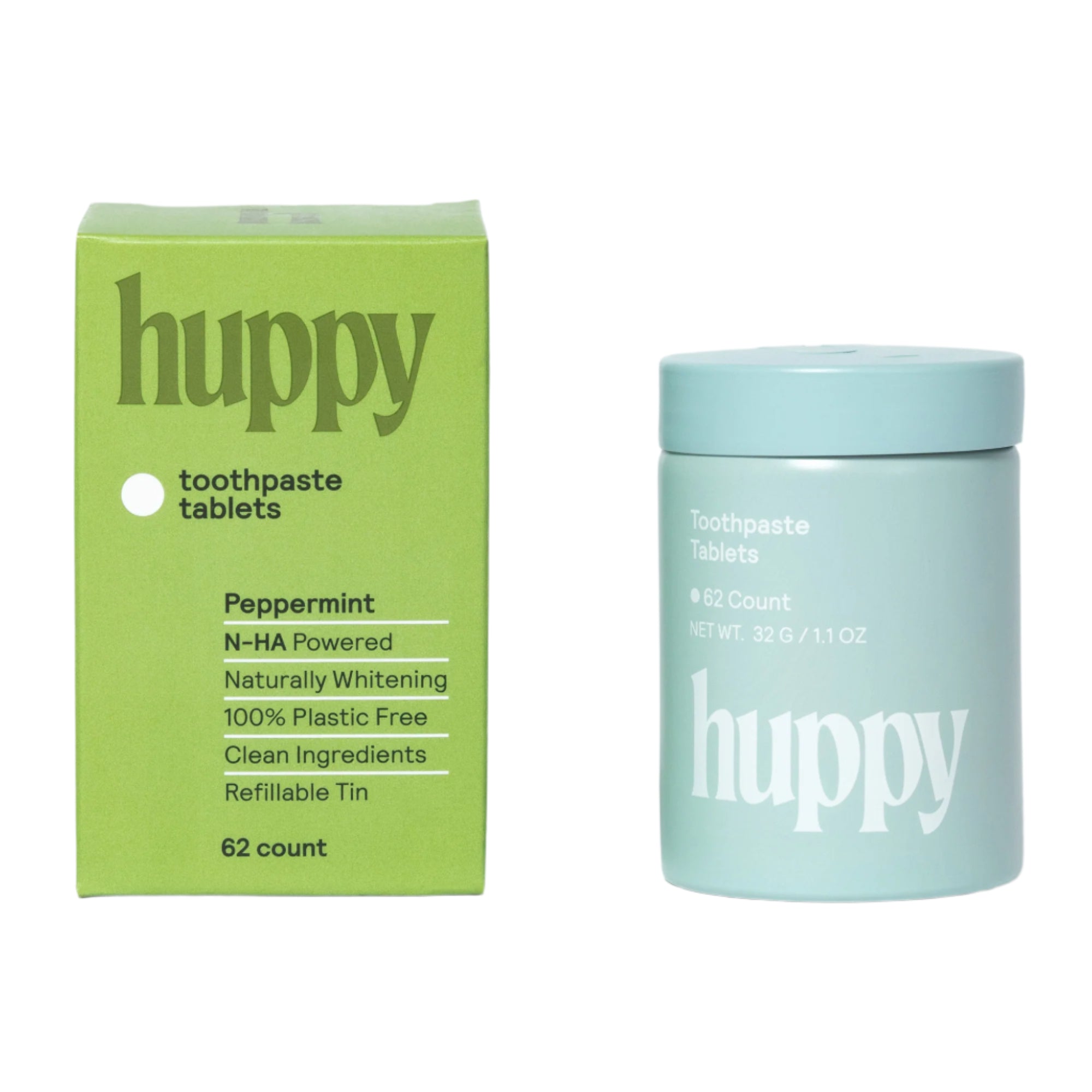 A green cardboard box and a closed light blue refillable tin for Huppy toothpaste tablets stand side-by-side. The packaging highlights the "Peppermint" flavor, it is "100% Plastic Free" and "N-HA Powered" with a "62 count."