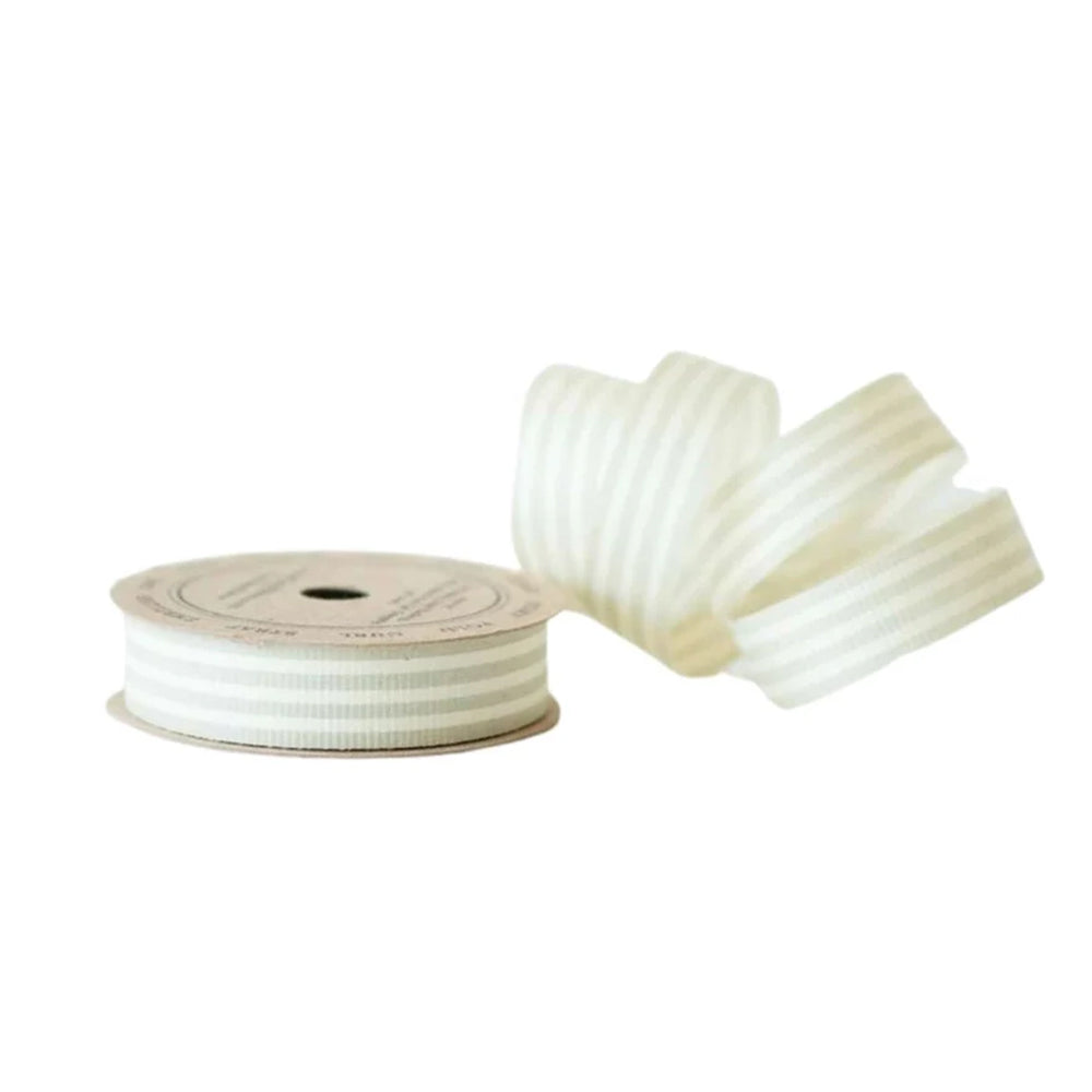 Spool of white ribbon with a few strands laid out on a white background