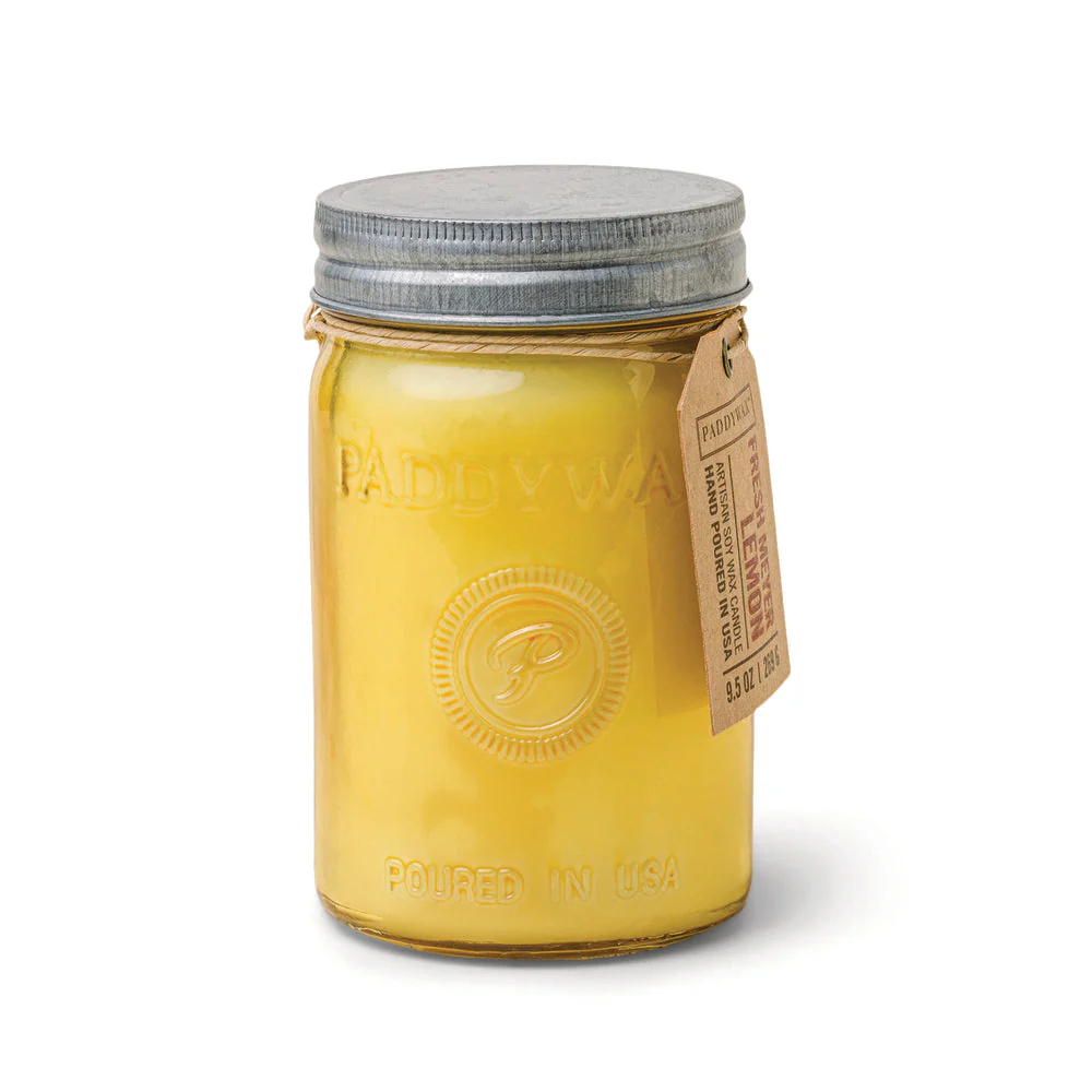A yellow Paddywax candle is shown in a glass jar with a metal lid. The tag identifies it as a Fresh Meyer Lemon artisan soy wax candle, hand-poured in the USA.