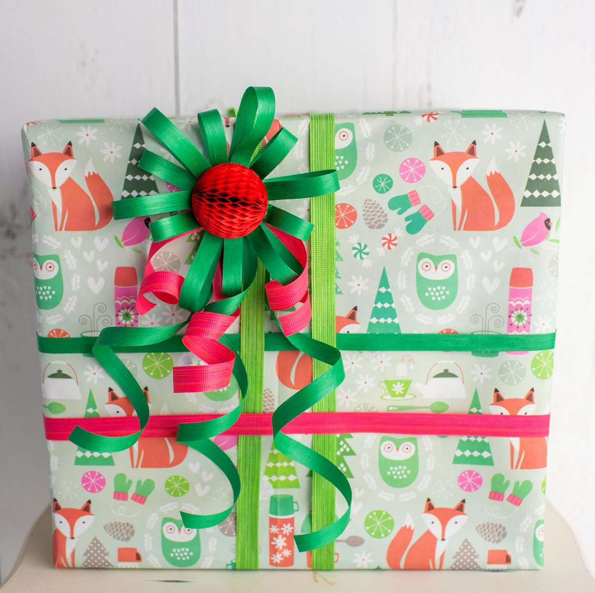 Rich red and green natural cotton curling ribbon tied around a wrapped gift, crafted from 100% cotton yarn dyed with eco-friendly water-based dyes. Compostable and sustainably made in the USA.