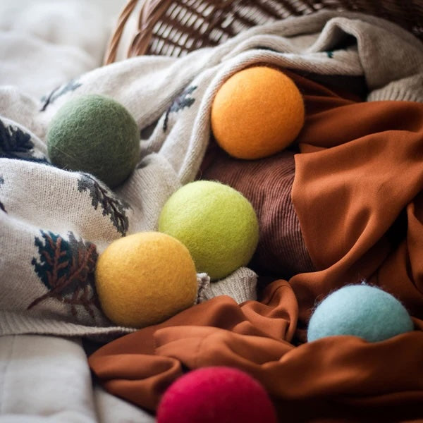 Six Harvest Moon wool dryer balls in warm fall tones scattered on cream fabric, eco-friendly and chemical-free, reduce drying time and static cling, made from 100% organic New Zealand wool.
