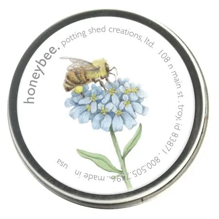 A silver tin of seeds with a white label on the lid. The label features a watercolor illustration of a honeybee on a cluster of light blue flowers, with the text 'honeybee. potting shed creations' around the edge.