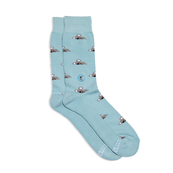A pair of light blue Conscious Step socks with a koala pattern is shown against a white background. A small koala logo is visible on the side of the sock.