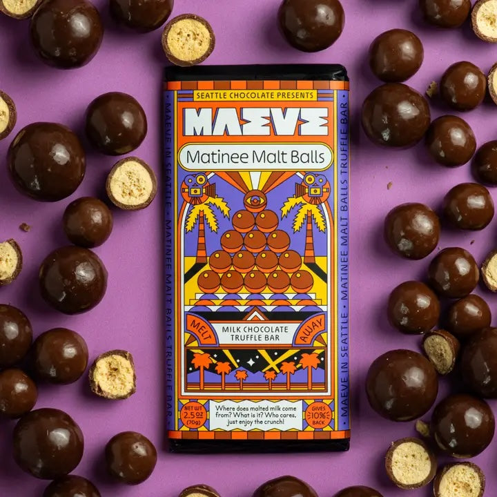 Maeve “Matinee Malt Balls” truffle bar placed among scattered malt balls, emphasizing the flavor inspiration and playful snack theme.