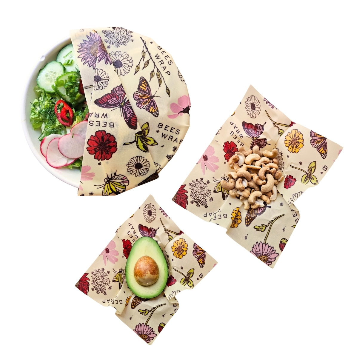 Three beeswax wraps with green botanical prints, each wrapping different foods: one with produce, one with avocado, and one with nuts.