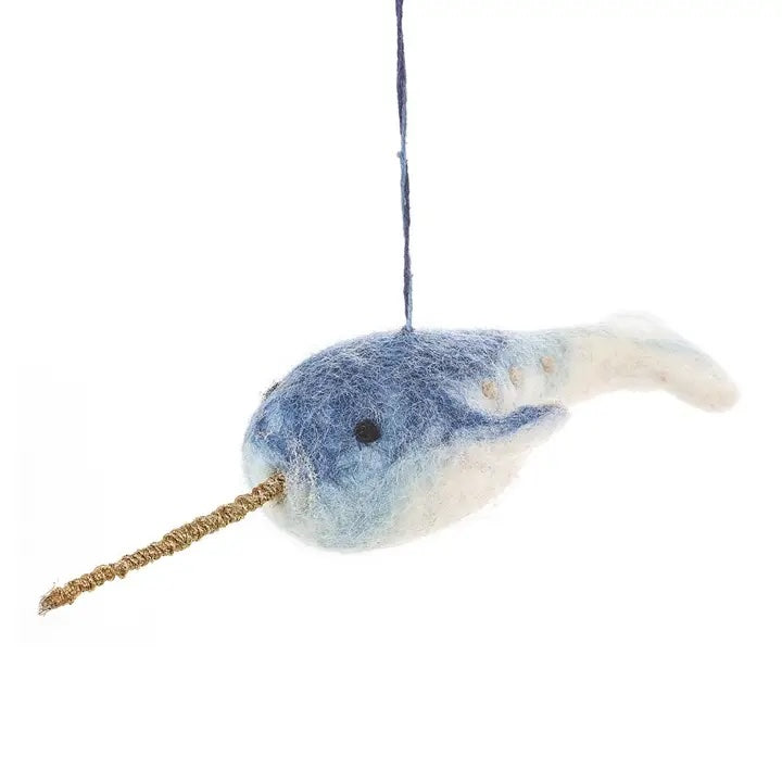 A handmade felt narwhal with a blue and white body and a long, woven brown horn is shown.