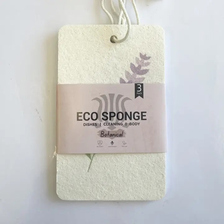 Pack of three compostable eco sponges with the paper sleeve label facing forward, designed to absorb 10x their weight and dry quickly.