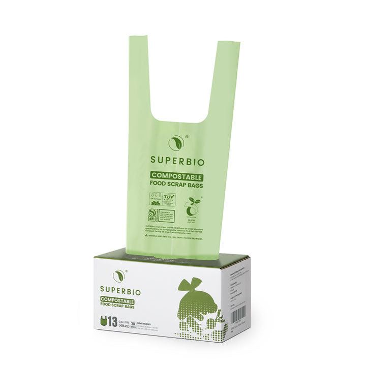 A green, compostable plastic bag with handles is shown standing inside a cardboard box. The box and bag are branded with the SUPERBIO logo and indicate they are 13-gallon compostable food scrap bags.