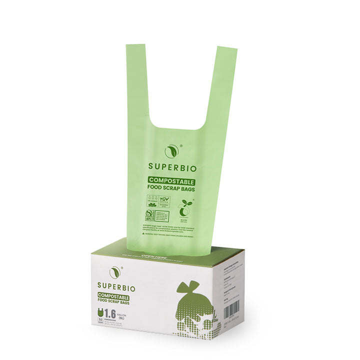 A box of "Superbio" compostable food scrap bags. The box is white with green text and a drawing of a skull wearing a hat made of leaves. A single light green bag is pulled up and visible from the top of the box.