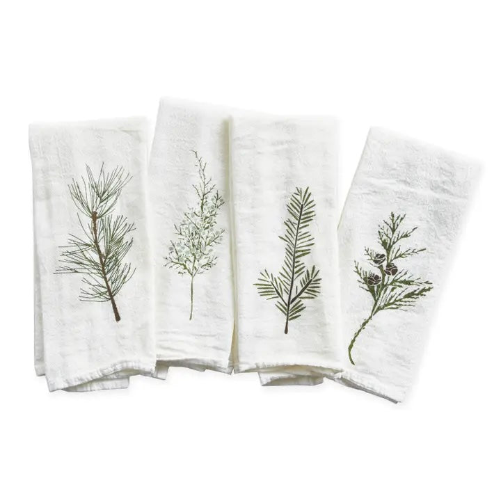 A sweet set of four white napkins is shown folded, each featuring a charming botanical print of a different evergreen or pine sprig in shades of green and brown.