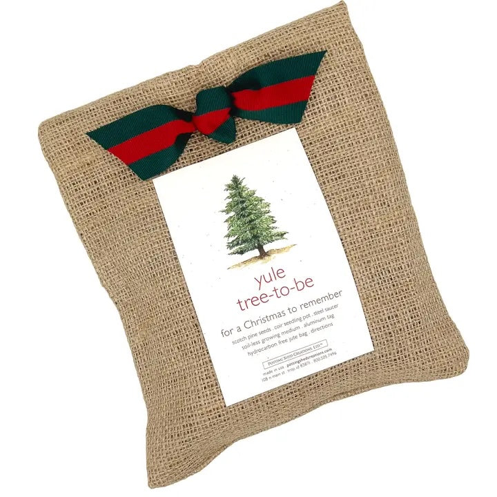 A "garden in a bag" burlap sack is tied with a festive red and green ribbon, with a card on top that says "yule tree to be" for a Christmas to remember. The card also mentions the contents include scotch pine seeds and a coir seeding pot.