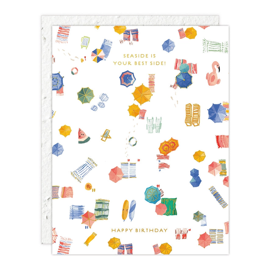 Seedling card with colorful beach umbrellas and towels scattered on white sand, captioned "Seaside is your best side! Happy birthday."