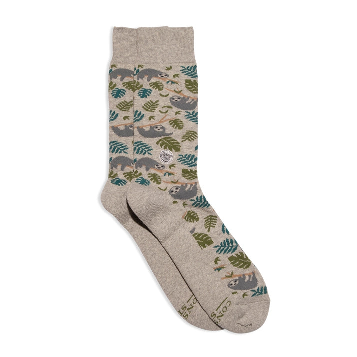 A pair of gray Conscious Step socks with a pattern of sloths and leaves is shown against a white background. The socks have a small sloth logo on the side and the brand name is visible on the bottom.