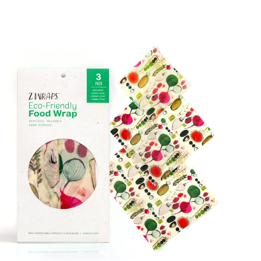 Three reusable beeswax food wraps in colorful vegetable patterns are folded and displayed on a neutral background, showing small, medium, and large sizes