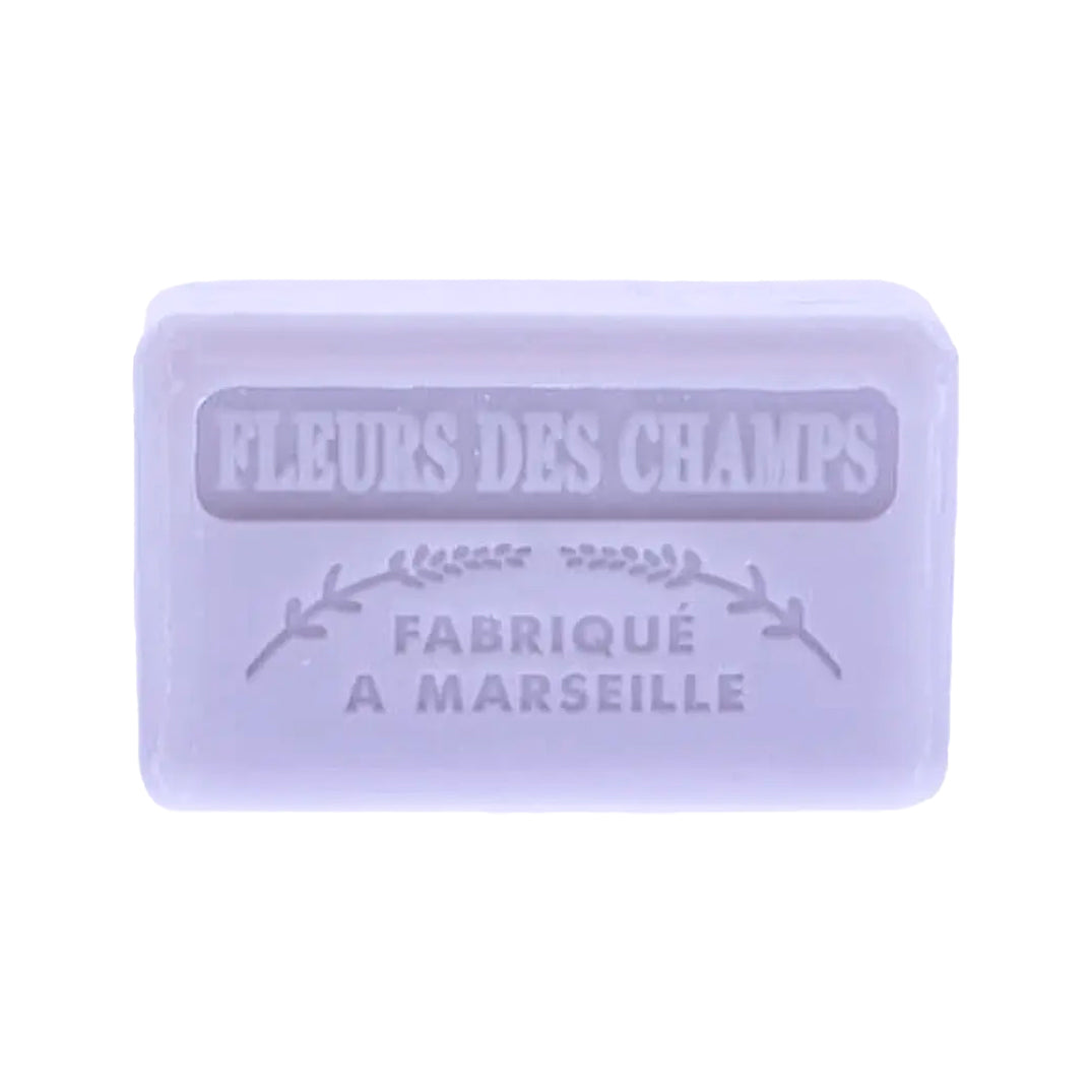 A French soap bar, "Fleurs Des Champs" is embossed with text that translates to "Made in Marseille". It is a light purple color.