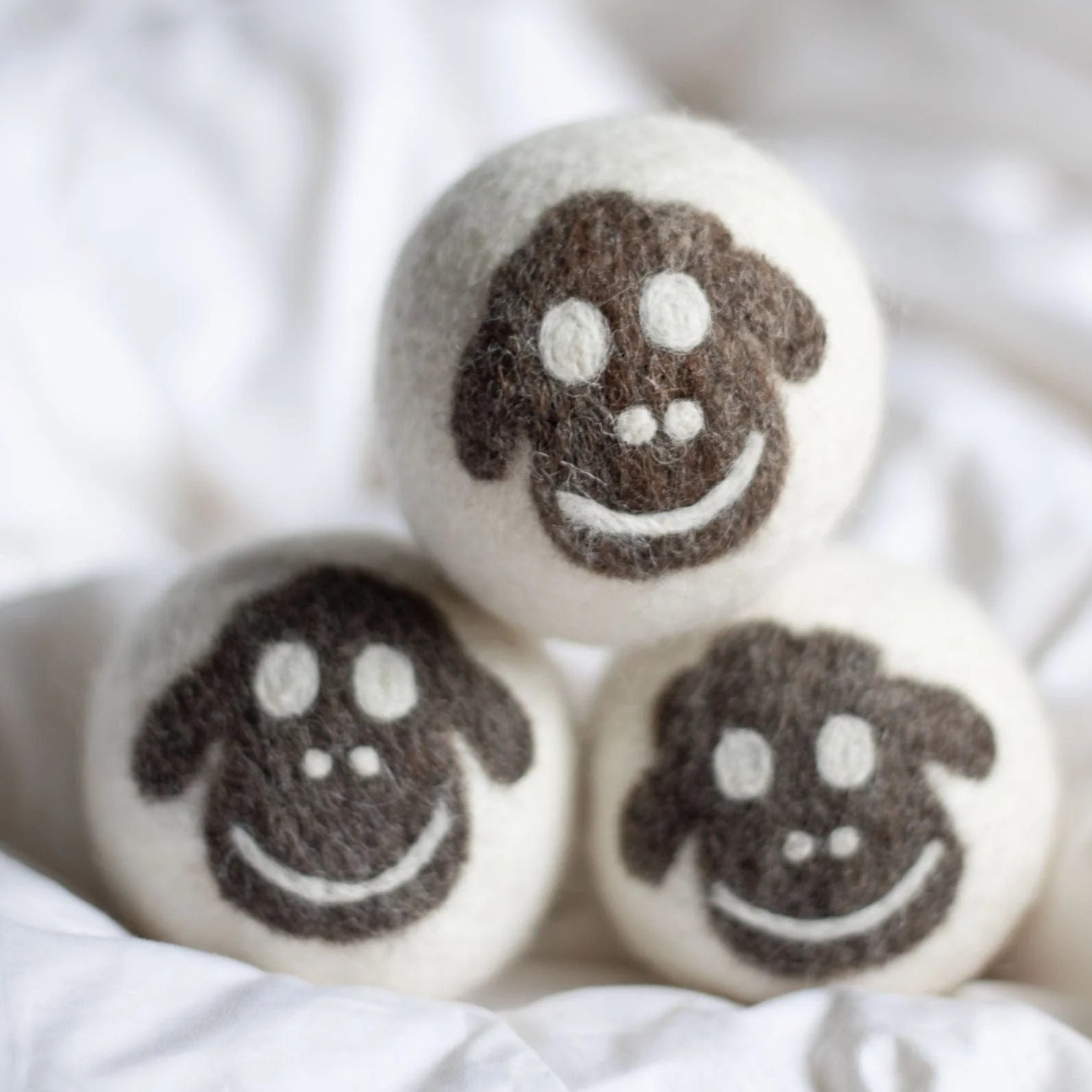 Three black sheep wool dryer balls resting on a folded towel, made from 100% organic New Zealand wool, cruelty-free and chemical-free, designed to reduce drying time and static while softening clothes naturally.