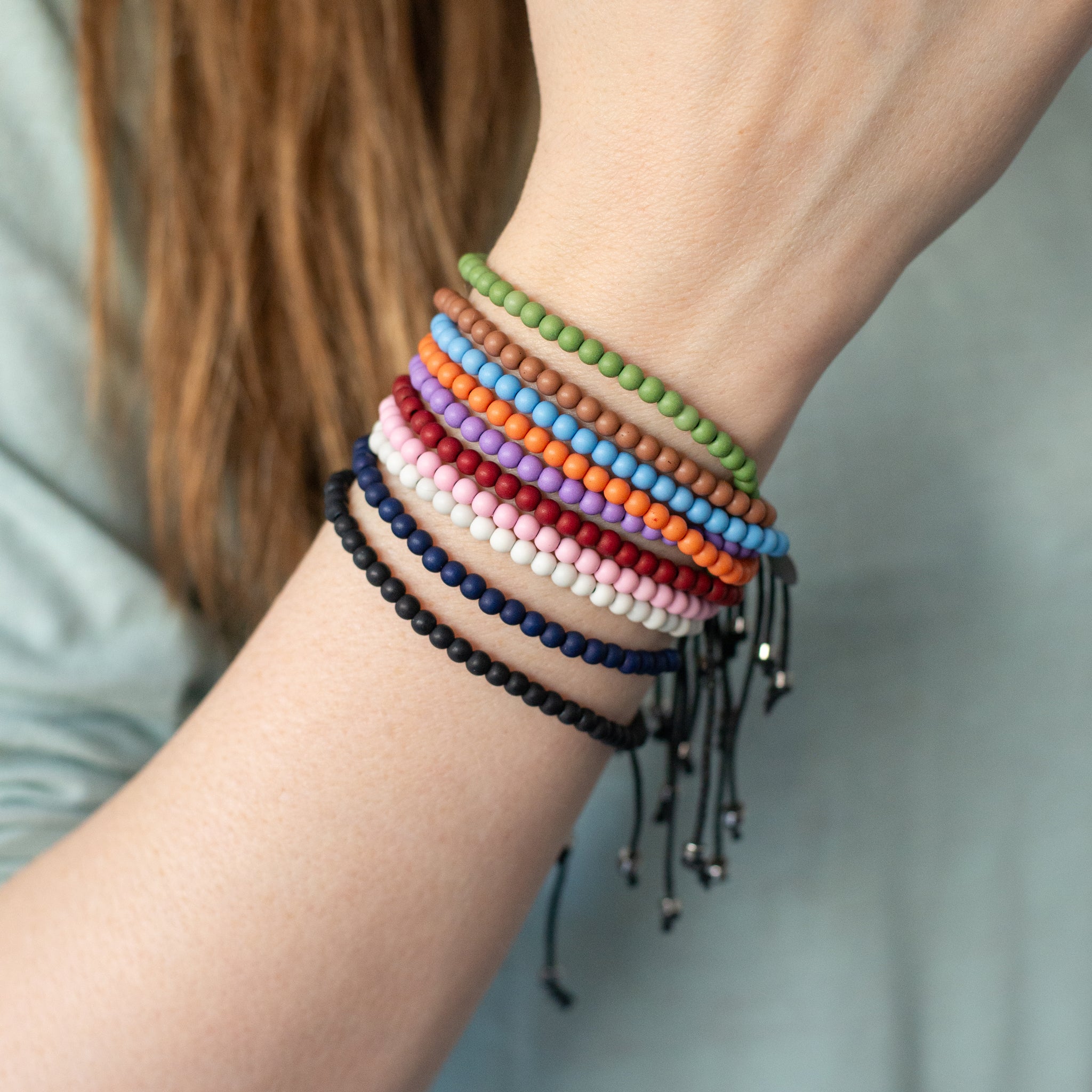 Wrist wearing multiple color recycled ocean plastic bracelets. Durable, adjustable, and handmade in Bali.