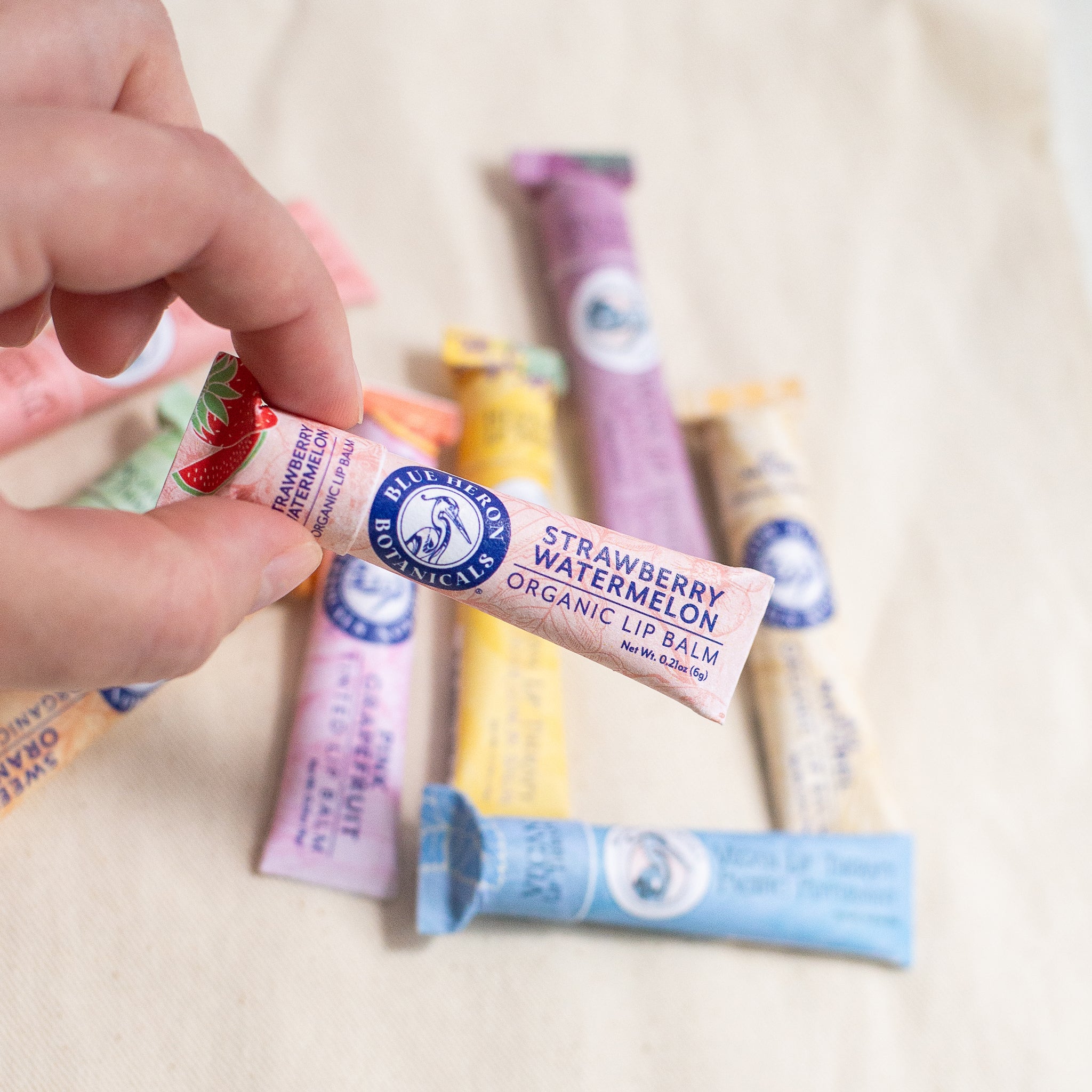 A colorful set of handcrafted lip therapy balms in scents like Pacific Mint, Coastal Berry, and Lavender Lemon—each made with organic, fair trade ingredients and packaged in compostable, plastic-free tubes.