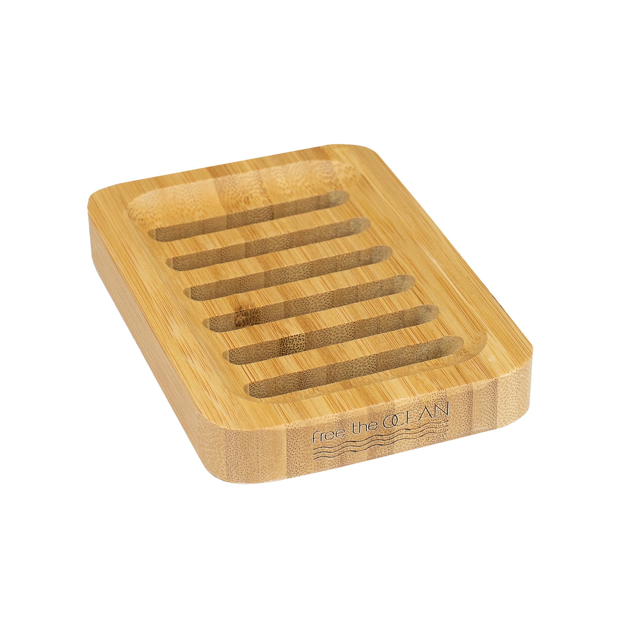 A rectangular bamboo soap dish is shown with a Free the OCEAN logo etched into its side. The dish has several parallel slats carved into its surface for drainage.