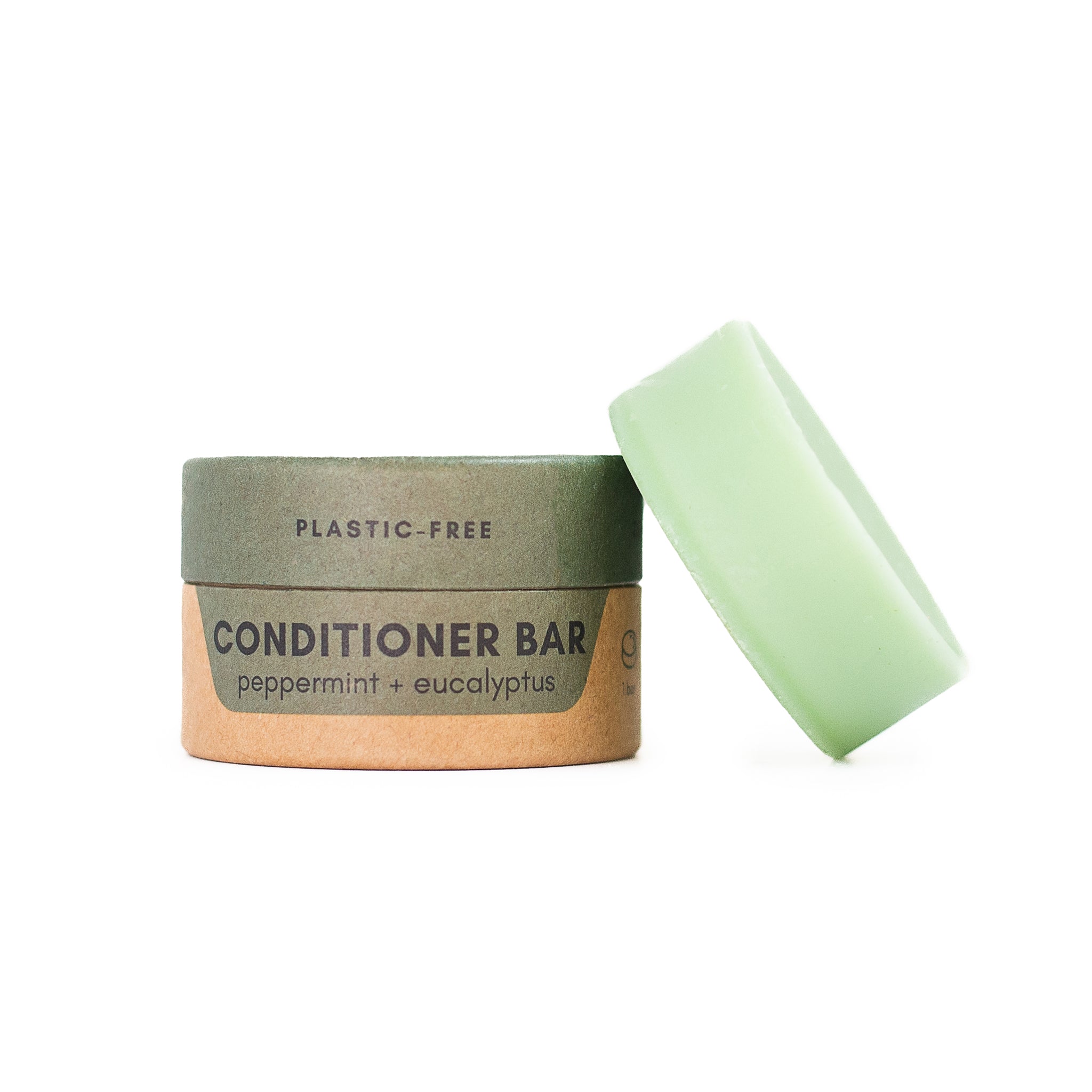 A "PLASTIC-FREE" cardboard container for "peppermint + eucalyptus" conditioner bar. A pale green ring-shaped bar leans against it.