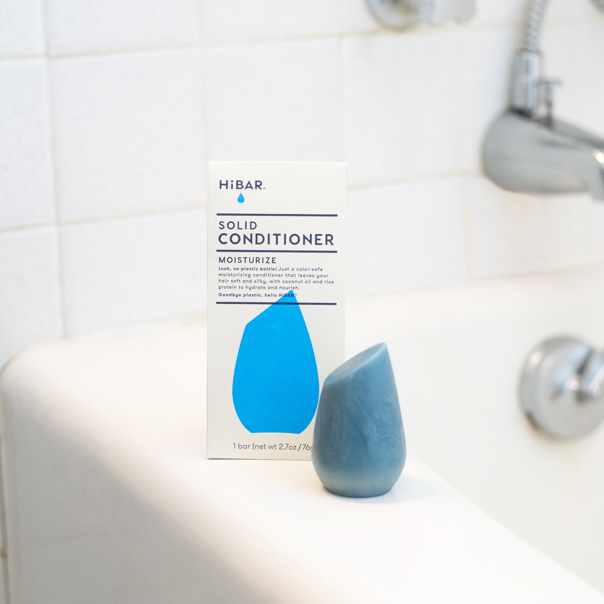 HiBar MOISTURIZE Solid Conditioner bar, light blue and tear-drop shaped, highlighting its plastic-free design, coconut oil, and rice protein ingredients for soft, silky hair