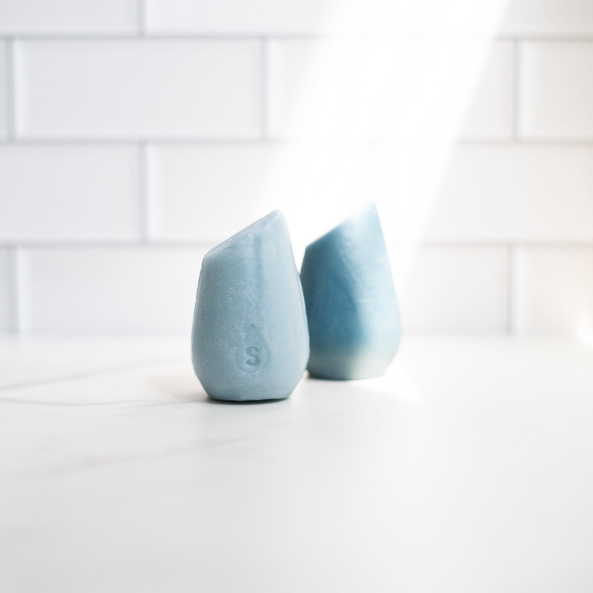 Image of the HiBar MOISTURIZE solid shampoo and conditioner bars next to each other featuring a streak of light shining on top of them.